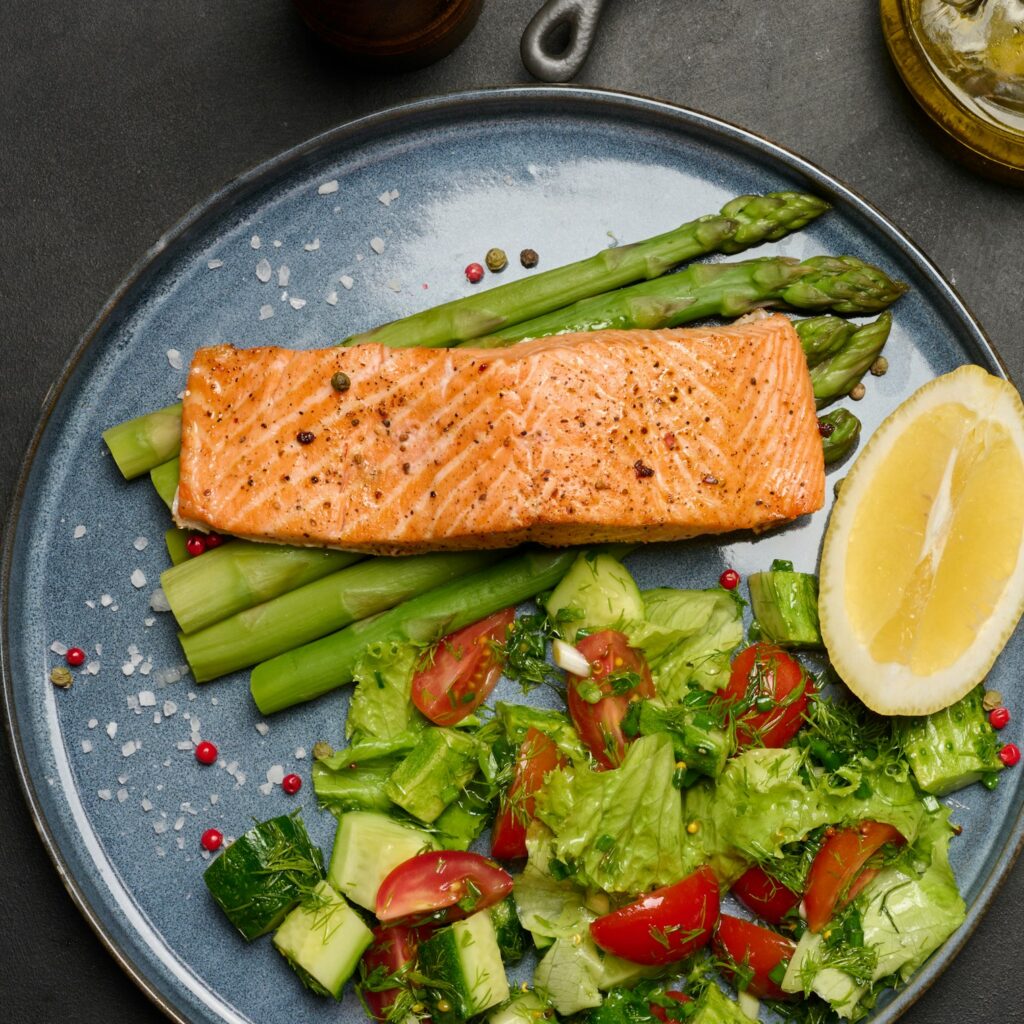 Healthy lunch with grilled salmon with asparagus and fresh tomato and cucumber salad